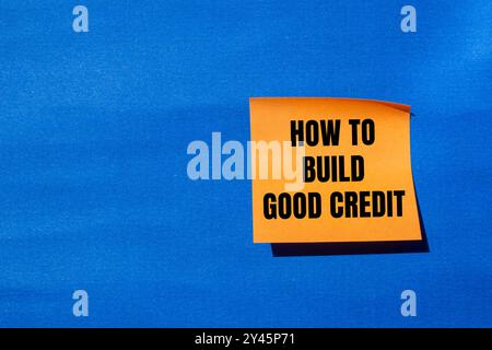 Comment construire un bon message de crédit écrit sur papier orange avec fond bleu. Conceptuel comment construire un bon symbole de crédit. Copier l'espace. Banque D'Images