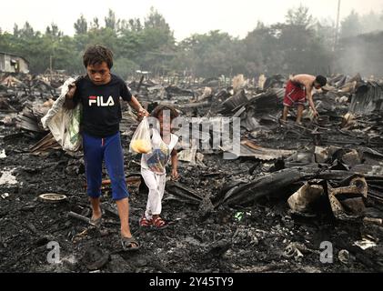 Séquelles d'un incendie dans le Bacoor, Cavite, au sud de Manille les frères et sœurs marchent parmi les débris de maisons brûlées causées par un incendie qui s'est produit la veille à Barangay Zapote, Bacoor, Cavite, le long du sud de Manille, Philippines, le 11 septembre 2024. Environ 1000 familles de colons informels vivant dans la zone côtière de Manille sont touchées par l'incendie, selon les responsables. Bacoor, Manille PHILIPPINES Copyright : xMatrixxImagesx/xNoelxCelisx Banque D'Images