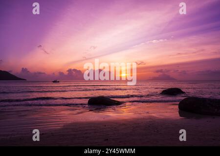 Photographie de paysage balnéaire avec sable humide et pierres côtières. Coucher de soleil à beau Vallon Beach, Seychelles Banque D'Images