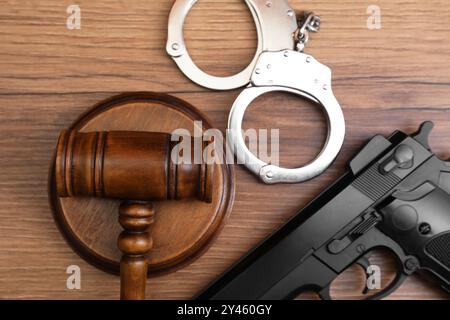 Marteau du juge, menottes et pistolet sur la table en bois, pose à plat Banque D'Images