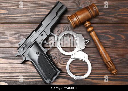 Pistolet, marteau de juge et menottes sur table en bois, pose à plat Banque D'Images