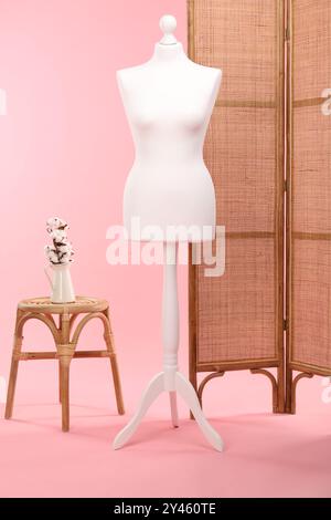 Mannequin féminin, écran pliant, tabouret et vase avec des fleurs de coton sur fond rose Banque D'Images