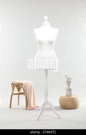 Un mannequin féminin sur support, tabouret, pouf et vase avec des fleurs de coton sur fond clair Banque D'Images