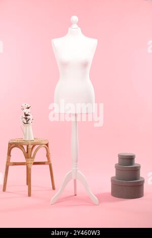 Mannequin féminin, boîtes, tabouret et vase avec des fleurs de coton sur fond rose Banque D'Images