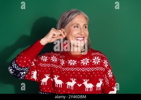 Photo de femme mignonne porter des vêtements imprimés à la mode tiennent l'atmosphère des jouets du nouvel an espace vide isolé sur fond de couleur verte Banque D'Images