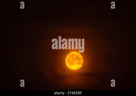 Lune avec des caractéristiques de surface visibles contre le ciel nocturne sombre, éclairant ses environs. Banque D'Images