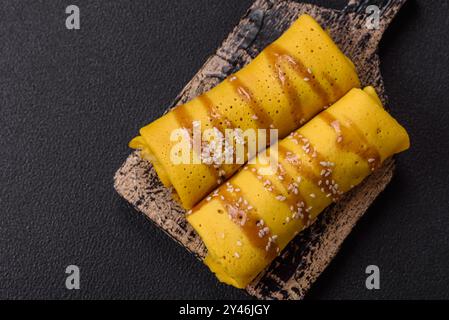 Crêpe sucrée ou salée avec différentes garnitures pour un petit déjeuner copieux sur un fond de béton foncé Banque D'Images