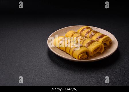 Crêpe sucrée ou salée avec différentes garnitures pour un petit déjeuner copieux sur un fond de béton foncé Banque D'Images