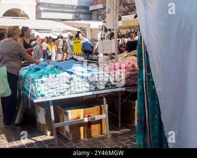 Cremona, Italie 31 août 2024 Une femme choisit un tissu sur un marché textile extérieur à partir d'un support de stalle en italie Banque D'Images