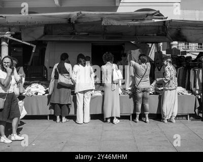 Cremona, Italie 31 août 2024 clients naviguant et achetant des vêtements dans un étal sur un marché de vêtements de plein air dans une ville italienne par un été ensoleillé Banque D'Images