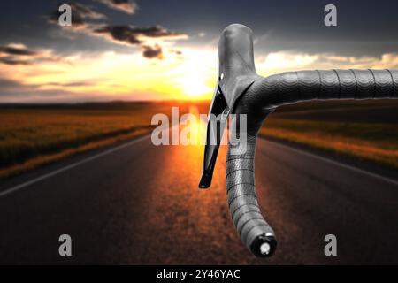 Guidon de vélo de route au coucher du soleil. Rouler à vélo sur une autoroute vide. Banque D'Images