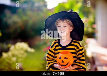 Les enfants se déguent en costume d'Halloween. Les enfants de couleur s'habillent avec un seau à bonbons dans la rue de banlieue. Petit garçon et fille trick ou traitement Banque D'Images