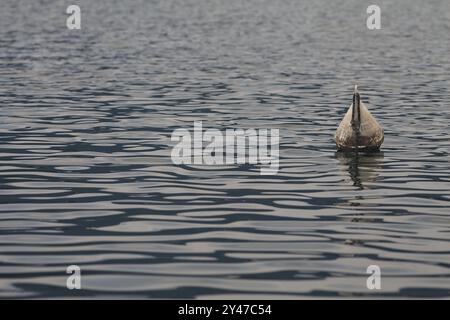 Bouy sur un lac au coucher du soleil avec son reflet coulé dans l'eau Banque D'Images