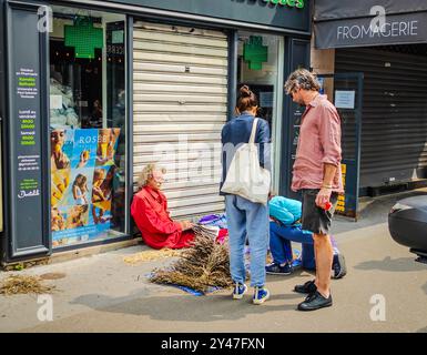 09 16 2024 - Paris, France. Des gens dans la rue à Paris achetant de la lavande à un vendeur de rue assis sur la rue Montmartre Banque D'Images