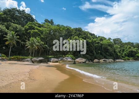 Paysage naturel de Prainha à Paraty, Brésil. Mer dans les tons de bleu turquoise, pierres, bande de sable et ciel bleu avec des nuages blancs. Banque D'Images