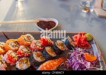 Belle vue rapprochée du plateau de sushi avec divers rouleaux, gingembre mariné, wasabi et sauce servie sur plateau, accompagné de baguettes. Banque D'Images