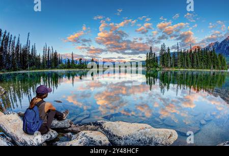 Jeune randonneuse saisissant le premier aperçu du lever de soleil doré de l'été au lac Pyramid dans le parc national Jasper, Alberta, Canada. HDR. Banque D'Images