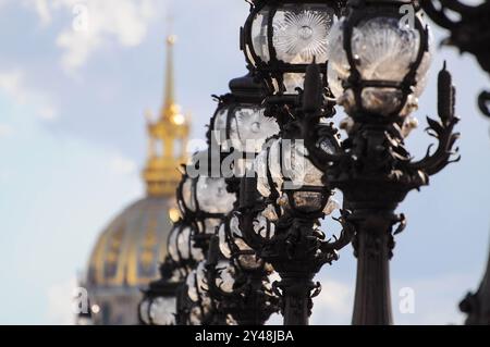 Des lampadaires ornés bordent une rue parisienne avec un dôme doré en arrière-plan. Banque D'Images