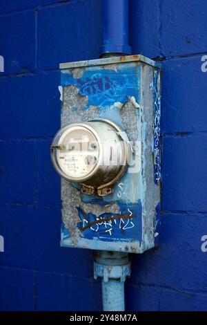 Compteur électrique avec graffiti urbain monté sur le mur bleu d'un bâtiment Banque D'Images