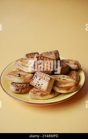 Une variété de délicieuses pâtisseries assorties magnifiquement disposées sur une assiette jaune vibrante Banque D'Images