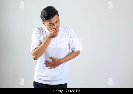 Homme asiatique mettant les mains sur son ventre ou son estomac Ache sur fond blanc. Santé concept médical Banque D'Images