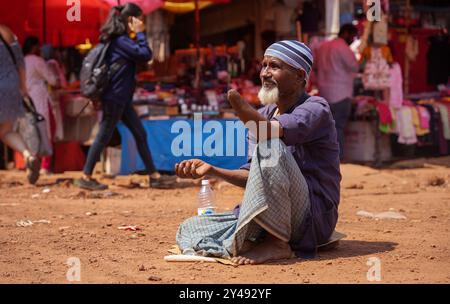 Mapusa, Inde - 19 février 2024 : un vieil homme est assis par terre avec un bras amputé et supplie pour l'aumône. Banque D'Images