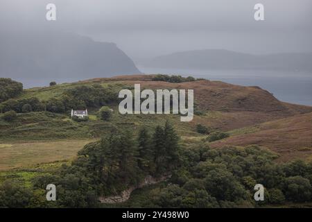 Une maison entourée de collines avec l'océan en arrière-plan sur l'île de Raasay, en Écosse. Banque D'Images