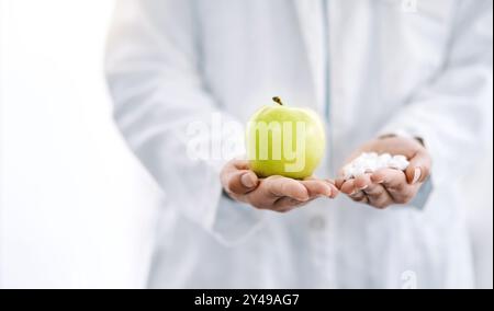 Mains, médecin et pomme avec des pilules en studio pour le choix médical, la prescription de médicaments et la décision de traitement. Personne, fruit et nutrition avec Banque D'Images