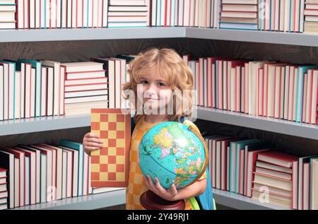 Garçon d'école avec globe du monde et échecs, enfance. École et enfants. Mignon enfant blonde avec un livre d'apprentissage. Journée du savoir. Banque D'Images