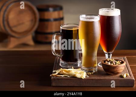 Verres avec différents types de bière et des collations sur la table en bois dans le bar. Espace pour le texte Banque D'Images