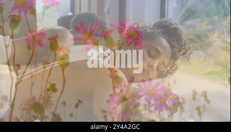 Image de fleurs roses dans le jardin sur la femme biraciale couchée sur la table de massage Banque D'Images