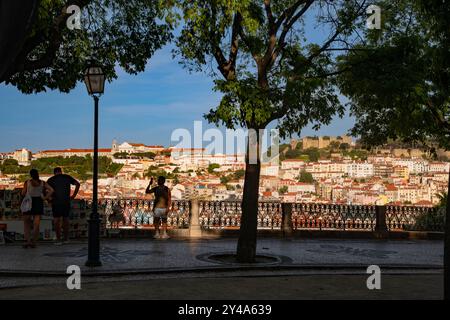 Une vue panoramique au coucher du soleil de Miradouro Sao Pedro de Alcantara d'un paysage urbain densément construit mis en évidence par le Castelo de Sao Jorge sur une colline . Banque D'Images