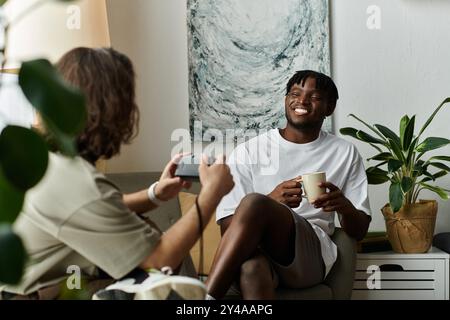 Un couple aime boire une boisson chaude et rire ensemble, entouré de plantes dans leur maison accueillante. Banque D'Images