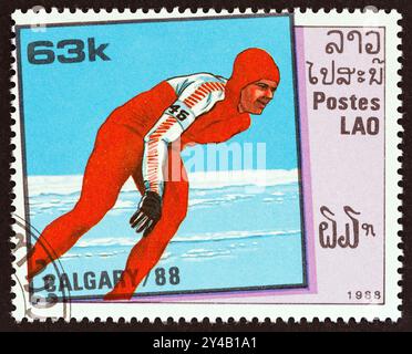 LAOS - VERS 1988 : un timbre imprimé au Laos à partir de l'émission des Jeux Olympiques d'hiver de Calgary montre le patinage de vitesse Banque D'Images