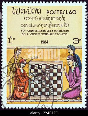 LAOS - VERS 1984 : un timbre imprimé au Laos montre quatre hommes à l'échiquier illustration du livre des échecs du roi Alphonse X. Banque D'Images