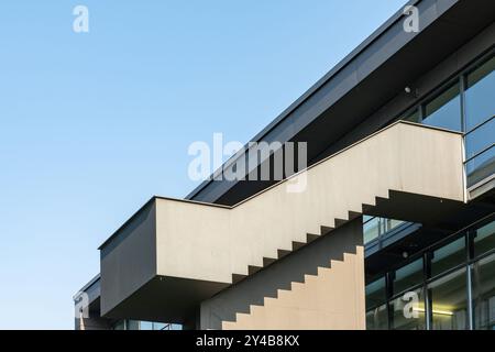Un bâtiment frappant dispose d'un escalier en porte-à-faux unique s'étendant vers l'extérieur, encadré contre un ciel bleu clair, mettant en valeur l'architecture contemporaine Banque D'Images