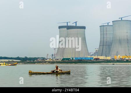 Bangladesh, Ruppur - 29.03.2024 : pêcheur en bateau sur le fleuve Gange, Padma avec tours de refroidissement de la centrale nucléaire de Rooppur en construction dans le Banque D'Images