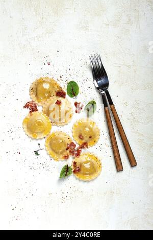 Raviolis frais, avec beurre, épices et herbes, bacon frit, sur la table, vue de dessus, fond clair, pas de gens Banque D'Images