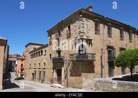 Bâtiment historique en grès avec balcon et armoiries sous un ciel clair, entouré d'arbres et de rues, Palacio de Justicia, Plasencia, CA Banque D'Images