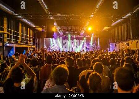 Concert rock dynamique en salle avec un public animé et des musiciens se produisant sur une scène bien éclairée, créant une atmosphère énergique remplie de mu Banque D'Images