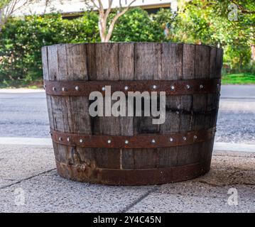 Jardinière de rue en fût de bourbon usagé montrant des douves de chêne altérées et des bandes rouillées. Banque D'Images