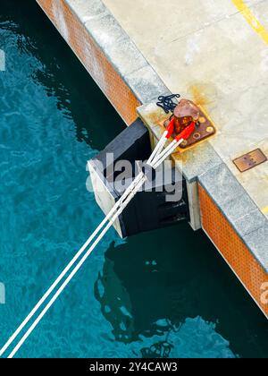 Cordes d'amarrage épaisses d'un navire tendu au poteau d'amarrage du quai en béton du port, corde pour immobiliser le navire, borne d'amarrage Banque D'Images