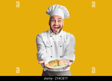 Chef Excité Montrant Plat Servant La Pose De Plat De Poisson, Studio Shot Banque D'Images