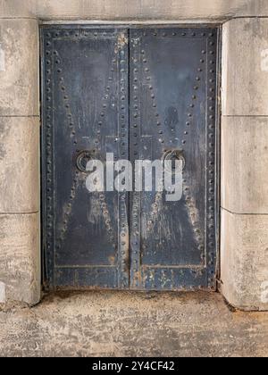 Portes industrielles en acier avec motifs de rivets et tirants à boucle forgée réglés dans une ouverture de bloc de béton Banque D'Images