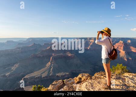 Jeune femme regardant à travers des jumelles les oiseaux sur le canyon, zoologie, écologie. Recherche dans la nature, observation des animaux Banque D'Images