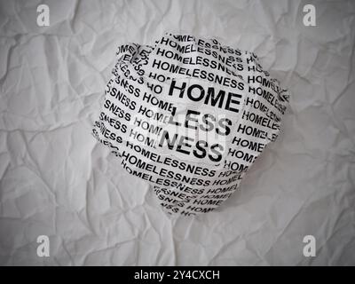 Boule de papier froissée avec des mots sans-abri sur un fond de morceaux de papier blanc déchiré. Banque D'Images