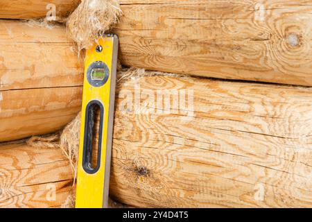 Le niveau de faisceau de la boîte jaune se trouve dans le coin de la nouvelle maison en rondins en construction Banque D'Images