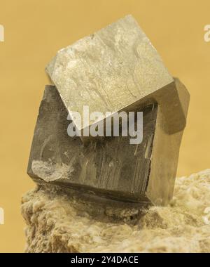 Formation de cristaux de pyrite sur une base rocheuse, capturée sur fond jaune Banque D'Images