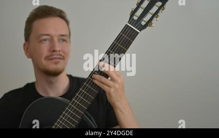 Un homme jouant de la guitare. Les mains sur les cordes. Portrait en gros plan. Sélection d'accord. Musicien jouant de la guitare électrique. Papier peint de bannière avec espace de copie Banque D'Images