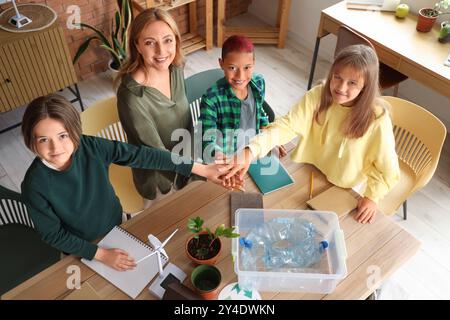 Enseignante avec des élèves qui mettent les mains ensemble en classe. Concept d'écologie Banque D'Images